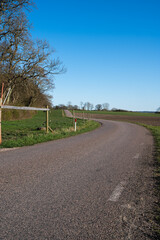 Wall Mural - An empty country side road bending through the rural farmland landscape in southern Sweden in springtime