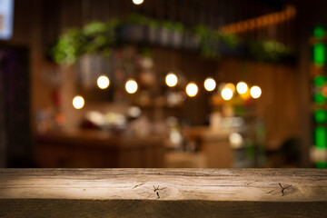 Empty wooden table top on blur light golden bokeh of cafe restaurant, bar in a dark background.