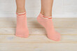 Woman feet in short pink cotton socks standing on toes on a white wood floor. Stand on tiptoe in low rise sports socks close-up.