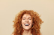 Hair. Redhead Girl Close Up Portrait. Cheerful Woman With Curly Red Hair Looking At Camera. Beautiful Female Against Beige Background. Face Expression And Natural Emotions.