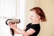© Ирина Фадеева - little girl in a blue dress with a drawing of a kitten dries hair with a hairdryer. Warm air blows in the face. Hair blows in different directions. short haircut. Profile. Smiles