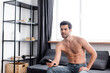 © LIGHTFIELD STUDIOS - positive sexy shirtless man holding remote controller while watching tv at home