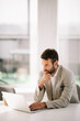 © JustLife - Portrait of handsome businessman. Man working on lap top and drinking coffee
