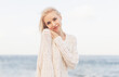Young blond woman on ocean coast in cool windy day