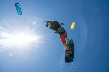 kiter does a difficult trick on a background of transparent water and blue sky