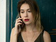 © Нигяр Гусейнова - Young charming woman calling with cell telephone while sitting alone in coffee shop during free time, attractive female with cute smile having talking conversation with mobile phone while rest in cafe