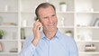 © stockbakers - Portrait of Cheerful Middle Aged Businessman Talking on Smartphone