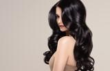 Beauty brunette girl with long  and   shiny wavy black hair .  Beautiful   woman model with curly hairstyle .
