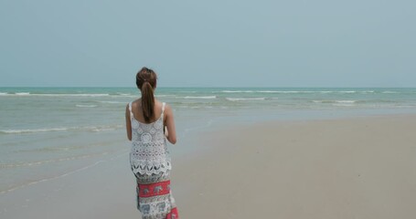 Canvas Print - Woman hold with her coconut drink and walk in the beach