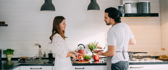 International Women's Day. Young couple in the morning in the kitchen at home