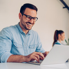 young businessman using laptop with a smile on his face