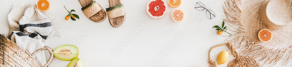 Summer mood layout. Flat-lay of natural espadrillas and sandals, straw sunhat, beach rafia and net bag, towel, sunglasses and fruit over white plain background, top view, copy space, wide composition - obrazy, fototapety, plakaty 