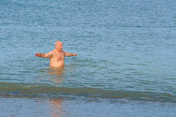 A man is swimming in the sea off the coast.