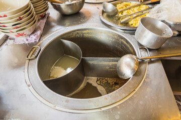 Wall Mural - The pot is prepared for cooking. The noodles are in low-light, boiling water with white smoke and steam on black background.