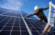 © anatoliy_gleb - Man electrician standing on ladder and installing photovoltaic solar panels under blue cloudy sky. Worker wearing safety helmet and gloves. Concept of alternative energy, power sustainable resources.