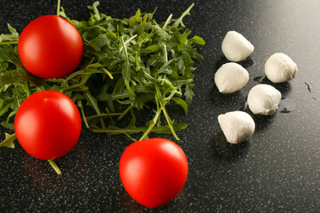 ingredients for salad with tomatoes, herbs and mozzarella on a dark background