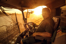 Operator Inside A Combine Harvester At Sunset
