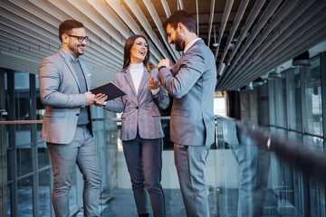 Group of cheerful caucasian elegant dressed real estate agents standing in the building in construction process and chatting. They taking a break form hard work. Woman in the middle holding tablet.a