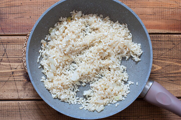 step-by-step cooking of shrimp risotto, step 2 - frying rice with onions, top view, selective focus