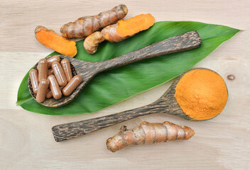 Canvas Print - Turmeric powder; Turmeric capsules in a wooden spoon on the leaves and wooden. Turmeric root is herb for good health.