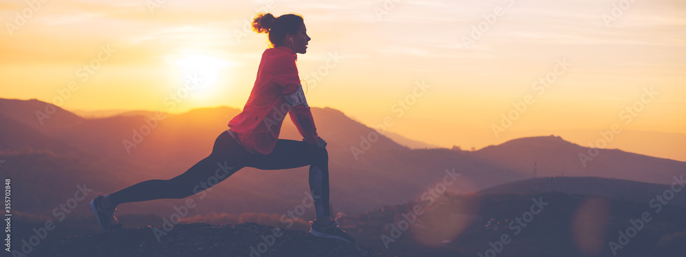 Silhouette of athletic girl doing stretching after a great jog in the mountains at sunset. Sport tight clothes. - obrazy, fototapety, plakaty 