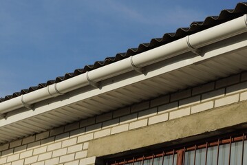 Wall Mural - long plastic white gutter pipes on the wall of the house under the roof