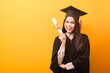 © tonefotografia - Portrait of happy Beautiful woman in graduation gown is holding education certificate on yellow background