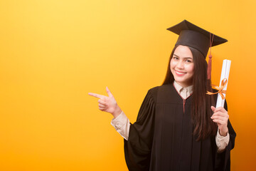 Portrait of happy Beautiful woman in graduation gown is holding education certificate on yellow background