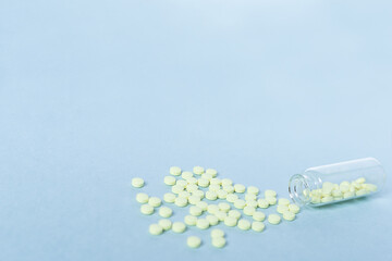 Yellow tablets and a glass bottle on a pastel blue background. Medicine, healthcare and the concept of tablets. Flatley. The view from the top. copyspace for text. blurred, blurred background