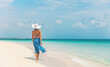 © Maridav - Caribbean beach vacation luxury elegant lady walking in blue beach wrap sarong skirt relaxing on idyllic holiday white sand beach stroll.