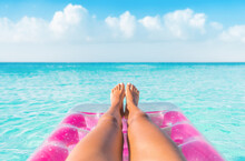 Summer Relax Vacation Woman Pov Of Legs Relaxing On Pink Inflatable Pool Toy Float Floating In Turquoise Water Ocean Background. Suntan At Tropical Beach.