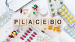 PLACEBO Word Written In Wooden Cubes on a white table with medicines and a stethoscope