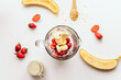 glass blender bowl filled with chopped fruit for a smoothie drink. top view. on the background are ingredients (bananas, strawberries, oat milk) Superfoods and healthy lifestyle or detox diet, vegan