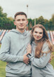 © Катя Данилюк - Girl hugs a guy. A girl and a guy in identical sweatshirts at the stadium