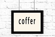 Black Frame Hanging On White Brick Wall With Inscription Coffer