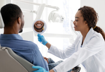 Wall Mural - Dentist holding mirror for patient to check whitening treatment result