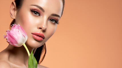 Wall Mural - beautiful white girl with flower. stunning girl with pink tulip. closeup face of young woman with a 