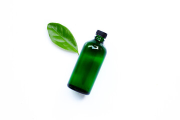 Wall Mural - Essential oil bottle with green leaf on white background.