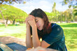 Teen girl praying outdoors at park table on sunny day
