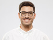 © Damir Khabirov - Young handsome smiling man wearing glasses and white shirt, isolated on gray background. Eyewear fashion or optics ads