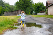 © Irina Schmidt - Little toddler girl wearing yellow rain boots, running and walking during sleet on rainy cloudy day. Cute happy child in colorful clothes jumping into puddle, splashing with water, outdoor activity