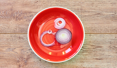 Wall Mural - bulb of sweet purple onion sliced in rings on a red plate on a wooden tabletop