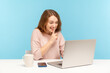 © khosrork - Please, keep secret. Positive young woman in casual clothes shushing with silence gesture, talking on video call, having online communication via laptop at home office. indoor studio shot isolated