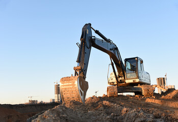 Wall Mural - Excavator during earthmoving at construction site. Backhoe digg ground at construction site for the construction of the road and laying sewer pipes district heating. Earth-moving heavy equipment