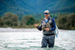 © TheSupporter - Close up of a fly fisherman casts his line while wading in the middle of a river
