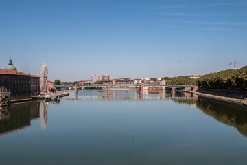 Wall Mural - Toulouse landmarks on the bank of river Garone. Hospital de La Grave and Ferries Wheel reflected in Garone river.