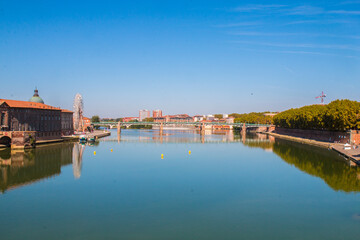 Wall Mural - Toulouse landmarks on the bank of river Garone. Hospital de La Grave and Ferries Wheel reflected in Garone river.