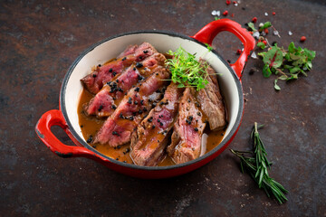 Wall Mural - Sliced medium-rare tenderloin steak with sauce on a plate, a dish of beef on an iron rusty background.