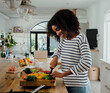 © Prins Productions - Young woman chopping vegetables in kitchen at home, happy and smiling
