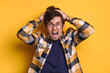 © Arsenii - Studio portrait of stressed man in angry, experiencing stress, madness, he furiously rips out his hair and screams. Isolated on yellow background. Copy space. Concept of mental health, human emotions